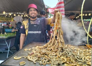 RUZAIZI Mohd. Zaid menunjukkan perut bulat bakar yang dijual di gerai Restoran Singgang Budu di Bazar Ramadan Shahbandar, Kuala Terengganu, semalam. - UTUSAN/KAMALIZA KAMARUDDIN