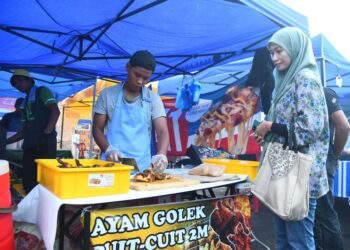 ADIK kepada Syarul Nizam Yusri memotong ayam golek yang dibeli oleh pelanggan di Bazar Ramadan Persiaran Wawasan, Gua Sami, Kangar, Perlis semalam.-UTUSAN/IZLIZAN OTHMAN