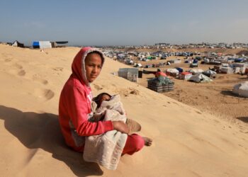 SEORANG gadis Palestin mendodoi adik kecilnya di atas bukit pasir menghadap ke kem pelarian di Rafah di selatan Semenanjung Gaza.-AFP