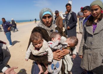 SEORANG wanita mendukung bayi kembar tiganya di bahagian tengah Gaza selepas melarikan diri dari pekarangan Hospital Al-Shifa, Bandar Gaza, kelmarin. -AFP