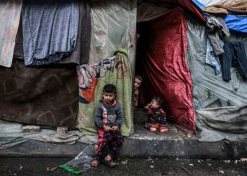 KANAK-KANAK Palestin yang dipindahkan menunggu di hadapan khemah sementara mereka di sebuah kem di Rafah pada 14 Mac lalu. – AFP