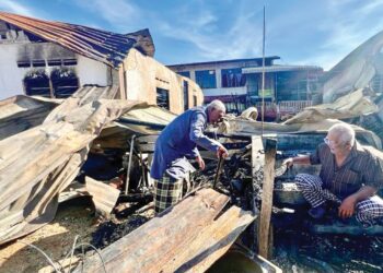 MAT Saad Mohamad (kanan) termenung di tangga batu sambil melihat adiknya, Mat Isa meninjau sisa kebakaran selepas kediaman mereka musnah dalam kebakaran di Kampung Seberang Ramai, Kuala Perlis kelmarin. – MINGGUAN/ASYRAF MUHAMMAD