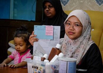 NOREEN Ismail menunjukkan rekod perubatan Nur Khayla Azzahra Mohamed Khairul Idhham ketika ditemui di kediaman keluarganya di Taman Desa Baru, Bukit Baru, Melaka. - UTUSAN/SYAFEEQ AHMAD