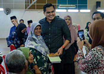 MUHAMAD AKMAL Saleh menyampaikan duit raya pada Majlis Penyampaian Sumbangan Aidilfitri Parlimen Jasin di Dewan MPJ Lipat Kajang, Jasin, Melaka. - UTUSAN/SYAFEEQ AHMAD