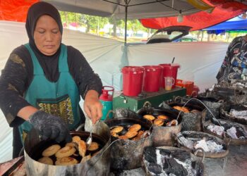 ARISUANI Ahmad membakar akok raja menggunakan arang kayu 
di  Kompleks Perdana Majlis Daerah Gua Musang, Kelantan, semalam. –UTUSAN/AIMUNI TUAN LAH