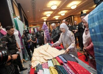 TENGKU Maimun Tuan Mat melihat seni tenunan kraf tangan semasa melawat pameran pada Hari Bersama Jabatan Penjara Malaysia di Istana Kehakiman, Putrajaya, hari ini. -UTUSAN/FAISOL MUSTAFA