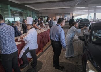 KAKITANGAN PICC mengagihkan kira-kira 3,000 pek bubur lambuk secara percuma kepada pemandu di PICC, Putrajaya. - UTUSAN/FAIZ ALIF ZUBIR