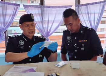 ROHAN Shah Ahmad (kiri) semasa mengambil barang kes di asrama Kolej Vokasional Lahad Datu hari ini.