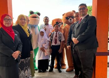 MOHD. Halim Arafulla (tengah) bersama guru dan maskot untuk menyambut kedatangan murid pada hari pertama persekolahan di SK Tasik Damai di Ipoh semalam. –  UTUSAN/LIYANA RAMLI