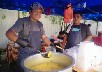 ZAMBRY Ahmad (kiri) menunjukkan hidangan menu istimewa ikan patin masak tempoyak yang dijualnya di Bazar Ramadan Bandar Baru Nilai, Seremban, Negeri Sembilan. - UTUSAN/NUR SHARIEZA ISMAIL.