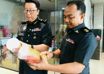 PEGAWAI penguatkuasa KPDN Perak memeriksa produk makanan ringan yang disita dalam serbuan di sebuah premis di Kawasan Perindustrian Jelapang, Ipoh semalam. - UTUSAN