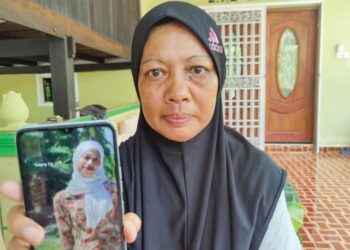 YUSNITA Abdullah Yusof menunjukkan gambar Allahyarham Izatul Azwa di Kampung Tebuk Jawa, Sungai Air Tawar, Sabak Bernam, Selangor. - FOTO/ ISKANDAR SHAH MOHAMED