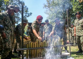 MUHAMMAD Hafizuddeain Jantan turut membakar lemang yang disediakan anggota Tentera Darat ketika menghadiri Majlis Hari Raya Aidilfitri bersama anggota bertugas di Kem Gubir, Sik. -UTUSAN/SHAHIR NOORDIN