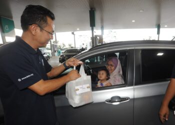 NORHELMI Tohid menyampaikan pek makanan berbuka puasa kepada pengguna jalan raya di stesen minyak Petronas di Lebuhraya Utara-Selatan  berhampiran Plaza Tol Skudai, Johor Bahru.