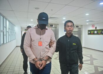 MUHAMAD Alif Abdul Jamal (kiri) yang tuduhan meminta dan menerima suapan dibawa keluar dari Mahkamah Sesyen, Kuala Terengganu, hari ini. - UTUSAN/PUQTRA HAIRRY ROSLI