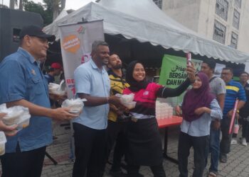 J. ARUL Kumar diiringi Hazahar (kiri) mengagihkan bungkusan lemang dan rendang kepada orang ramai di pada Program Ihya Ramadan Bersama Jabatan, Agensi dan Masyarakat Setempat di Bazar Ramadan Bandar Baru Nilai di Seremban.-UTUSAN/NUR SHARIEZA ISMAIL.