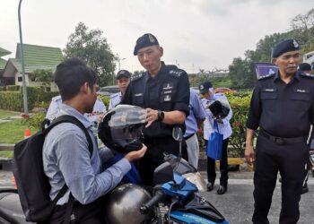 AHMAD Dzaffir Mohd. Yussof menyampaikan topi kaledar kepada penunggang motosikal pada Op Selamat 22/2024 Sempena Hari Raya Aidilfitri di Plaza Tol Nilai, Nilai, Seremban hari ini.-UTUSAN/NUR SHARIEZA ISMAIL