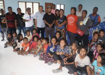 RAZAK Daud (berdiri, lima dari kiri) menyantuni saudara baharu perkampungan Orang Asli Kampung Sungai Bangkong di Jerantut, Pahang.