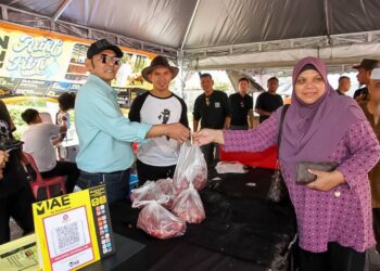 JAMAL Abdillah (kiri) pada program jualan daging lembu pada harga Rahmah sempena Aidilfitri di pekarangan bangunan MBI di Ipoh hari ini. - UTUSAN