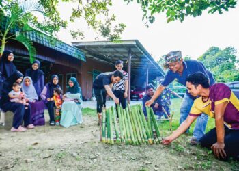 MOHAMAD Jusoh (dua dari kanan) bersama anak serta menantunya membakar lemang untuk dijadikan juadah istimewa sempena menyambut  Hari Raya Aidilfitri di Kampung Pulau Kudat, Kuala Berang, Hulu Terengganu, kelmarin. – UTUSAN/PUQTRA HAIRRY ROSLI