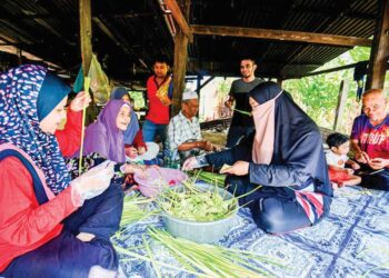 ABDULLAH Md. Amin (tengah) dan Ramlah Endut (dua dari kiri) bersama anak serta cucunya menganyam ketupat untuk dijadikan juadah pada Hari Raya Aidilfitri di rumah mereka di Kampung Surau Panjang, Marang, kelmarin. – UTUSAN/PUQTRA HAIRRY ROSLI