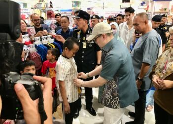 TENGKU Muhammad Fakhry Petra (tiga dari kanan) memakaikan baju raya kepada penerima di AEON Mall Kota Bharu, Kelantan hari ini.- UTUSAN/ ROSLIZA MOHAMED.