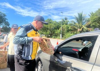 DR. Izani Hussin(kiri) menyampaikan bungkusan hari raya kepada perantau selepas selepas mengadakan lawatan ke lokasi pembaikan jalan di lalaun Kuala Terengganu-Kota Bharu di Bukit Yong, Pasir Puteh, Kelantan hari ini- UTUSAN/TOREK SULONG