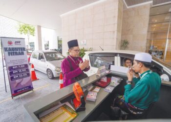 AMIL zakat, Mohamad Syakir Azmi (kanan) mengaminkan bacaan doa selepas menerima pembayaran zakat fitrah melalui kaunter pandu lalu di Masjid Tuanku Mizan Zainal Abidin, Putrajaya, semalam. - UTUSAN/FAISOL MUSTAFA