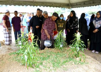 KASIMON Kasban menyiram kubur anak dan menantunya pada pengebumian di Tanah Perkuburan Islam Kampung Paya Panjang di Padang Rengas hari ini. -  UTUSAN/ZULFACHRI ZULKIFLI.