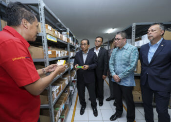 MOHAMED Khaled Nordin bersama Pengerusi Pharmaniaga, Izaddeen Daud (dua dari kanan) mendengar penerangan mengenai produk Pharmaniaga ketika melawat kilang PT. Millennium Pharmacon International Tbk di Bogor, dekat Jakarta, Indonesia hari ini.  Turut hadir, Syed Md. Hasrin Tengku Hussin (kanan) dan Isham Ishak. - UTUSAN/FARIZ RUSADIO