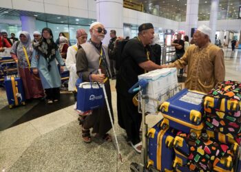 MD Daud Che Ngah ketika menyambut ketibaan jemaah umrah OKU penglihatan di KLIA Terminal 1. - UTUSAN/FAISOL MUSTAFA