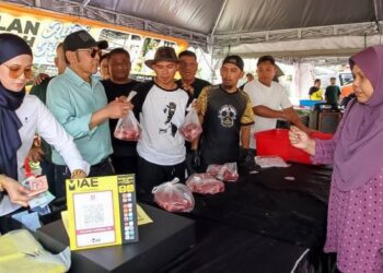 JAMAL Abdillah (kiri) pada program jualan daging lembu raya pada harga Rahmah di pekarangan bangunan MBI di Ipoh semalam.