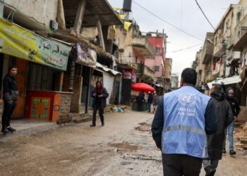 SEORANG lelaki yang memakai jaket Pertubuhan Bangsa-Bangsa Bersatu bagi Pelarian Palestin (UNRWA) memantau sepanjang penempatan  warga Palestin yang musnah akibat dibedil Israel, baru-baru ini.  - AFP