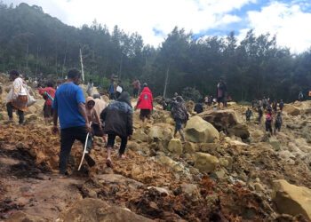 This handout photo by the International Organization for Migration (IOM) on May 25, 2024 shows locals walking on top of a landslide at Yambali Village in the region of Maip Mulitaka, in Papua New Guinea's Enga Province. Rescue teams began arriving at the site of a massive landslide in Papua New Guinea's remote highlands on May 25, helping villagers search for the scores of people feared dead under the towering mounds of rubble and mud. (Photo by BENJAMIN SIPA / International Organization for Migration / AFP)