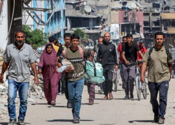 ORANG ramai bergerak melepasi bangunan yang musnah di sepanjang jalan di Khan Younis, selatan Gaza, kelmarin.-AFP