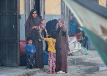 DUA wanita melihat rakyat Palestin memeriksa bot yang rosak dalam kebakaran di Rafah. selatan Gaza, semalam. -REUTERS