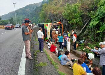 KEADAAN bas persiaran yang terbabas dan terbalik dalam longkang di Kilometer 264.5, Lebuh Raya Utara-Selatan arah selatan berhampiran Terowong Menora di Ipoh hari ini.  - UTUSAN/IHSAN JBPM