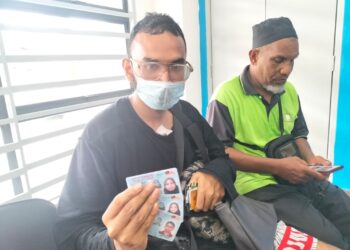 RASHID menunjukkan kad pengenalan milik ahli keluarganya yang terkorban dalam kebakaran membabitkan rumah kedai dua tingkat 
di Jalan Balik Pulau, Pulau Pinang, pagi semalam.