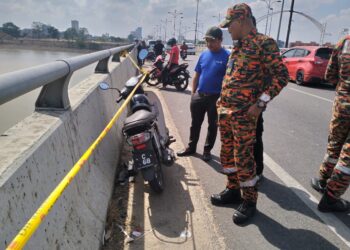 RAMLI Abdullah (kanan) memeriksa motosikal yang ditinggalkan mangsa di atas Jambatan Sultan Yahya Petra, Kota Bharu, Kelantan hari ini-UTUSAN/ROHANA ISMAIL.