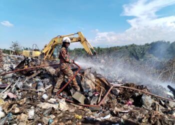 ANGGOTA bomba memadamkan kebakaran di pusat pelupusan sampah di Kampung Paya Rawa, Besut, hari ini. - UTUSAN/WAN ZURATIKAH IFFAH WAN ZULKIFLI