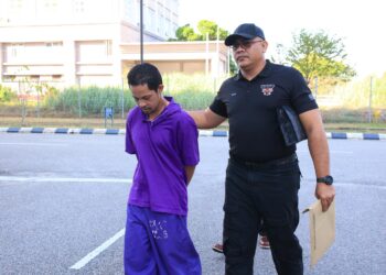 TERTUDUH diiringi polis semasa menghadiri prosiding perbicaraan di Mahkmah Sesyen Kota Bharu, Kelantan hari ini-UTUSAN/KAMARUL BISMI KAMARUZAMAN.