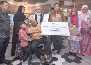 Khairul Azmir Abdul Hamid (berkerusi roda) menerima Faedah Pencen Ilat daripada Mohamad Asri Ngosman di Ibu pejabat Yayasan Nurjiwa, Kuala Lumpur, semalam. – UTUSAN/M Firdaus M Johari