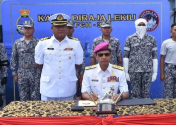 ABDUL Rahman (duduk) bersama anggota TLDM yang mengenakan pakaian operasi baharu semasa majlis pelancaran di atas kapal KD Lekiu hari ini.