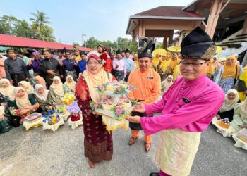 ZURINA Ripin (kiri) mewakili ibu bapa menyerahkan sumbangan pulut semangat kepada Muhamad Jamil (kanan) di SMK Seri Aman, Pasir Puteh, Kelantan hari ini.-UTUSAN/TOREK SULONG