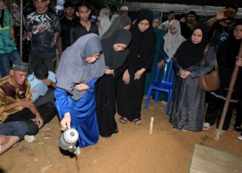 IBU Allahyarham  Konstabel Ahmad Azza Fahmi Azhar, Nor Haliza Awaluddin menyiram air di kubur anaknya pada pengebumian di Bidor hari ini. - UTUSAN/ZULFACHRI ZULKIFLI