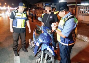 MUHAMMAD Kifli Ma Hassan (kanan) memeriksa lesen memandu seorang penunggang motosikal semasa Op Khas Hari Raya Aidiladha di Akademi JPJ Timur di Jalan Kuala Krai, Kota Bharu, Kelantan. - UTUSAN/ ROHANA MOHD. NAWI