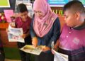 GURU Besar STB, Nor Zaiton Ibrahim (tengah) bersama murid-murid membaca sisipan khas Utusan Pelajar di STB, Arau, Perlis. – UTUSAN