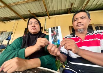 ROHANI Jaafar (kiri) dan suami, Zunizam Ismail menunjukkan gambar kakaknya, Rokiah,60, yang dilaporkan hilang sejak seminggu lalu ketika ditemui di rumah mereka di Kampung Guring Bawah, Pauh, Perlis semalam.- UTUSAN/MOHD. HAFIZ ABD. MUTALIB