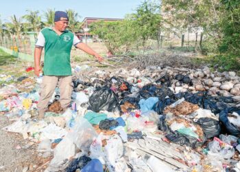 SUHAIRI Mat Nor menunjukkan sebahagian longgokan sampah di sekitar pagar Tanah Perkuburan Islam Dato’ Raja Dagang Semerak, Pasir Puteh, Kelantan kelmarin. – UTUSAN/TOREK SULONG