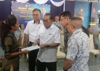 MOHAMED Khalid Nordin (tengah) menyampaikan sumbangan caruman Lembaga Tabung Angkatan Tentera (LTAT) kepada Dr. S. Harshini, balu kepada Leftenan T. Sivasuthan, yang terkorban dalam nahas dua helikopter, 23 April lalu. - UTUSAN